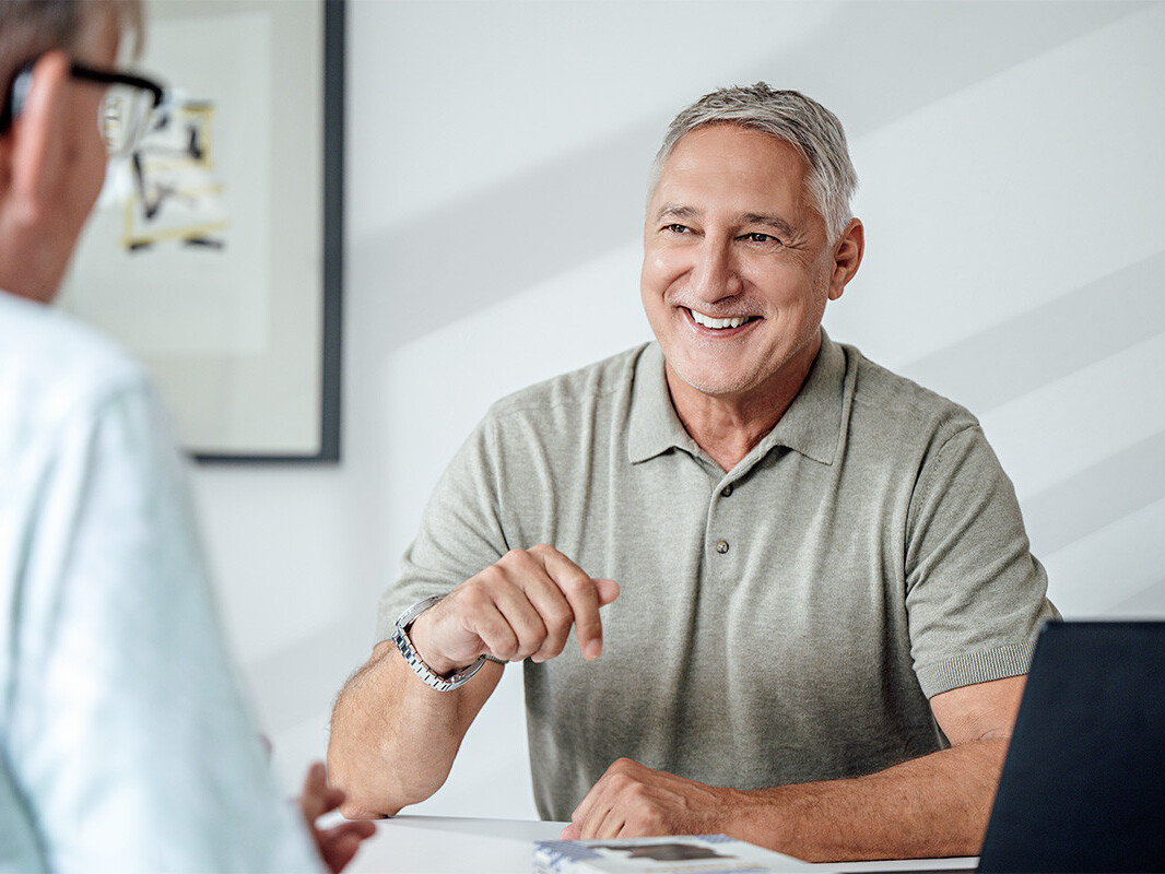Smiling older man in consultation pointing during meeting with doctor in bright office, healthcare services.