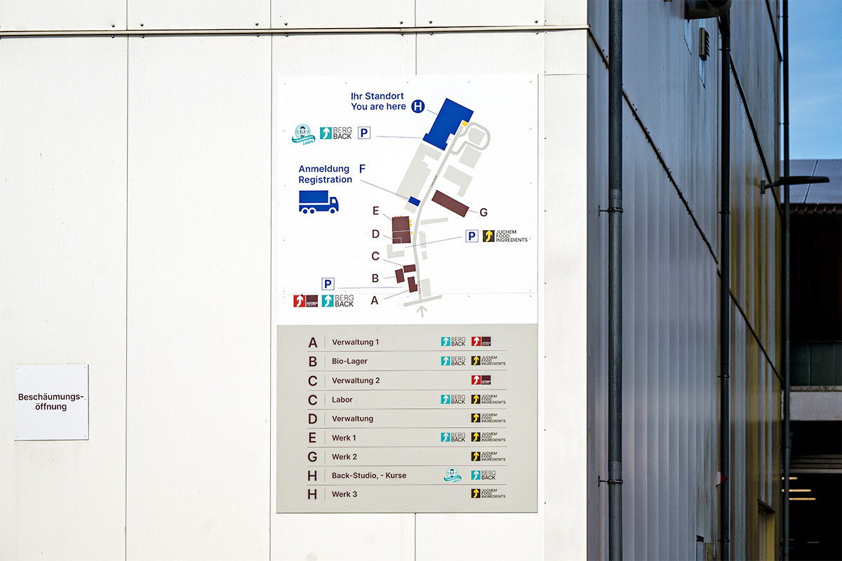 Directional map sign with entrances and rooms inside a building corridor, showing registration, offices, and parking areas