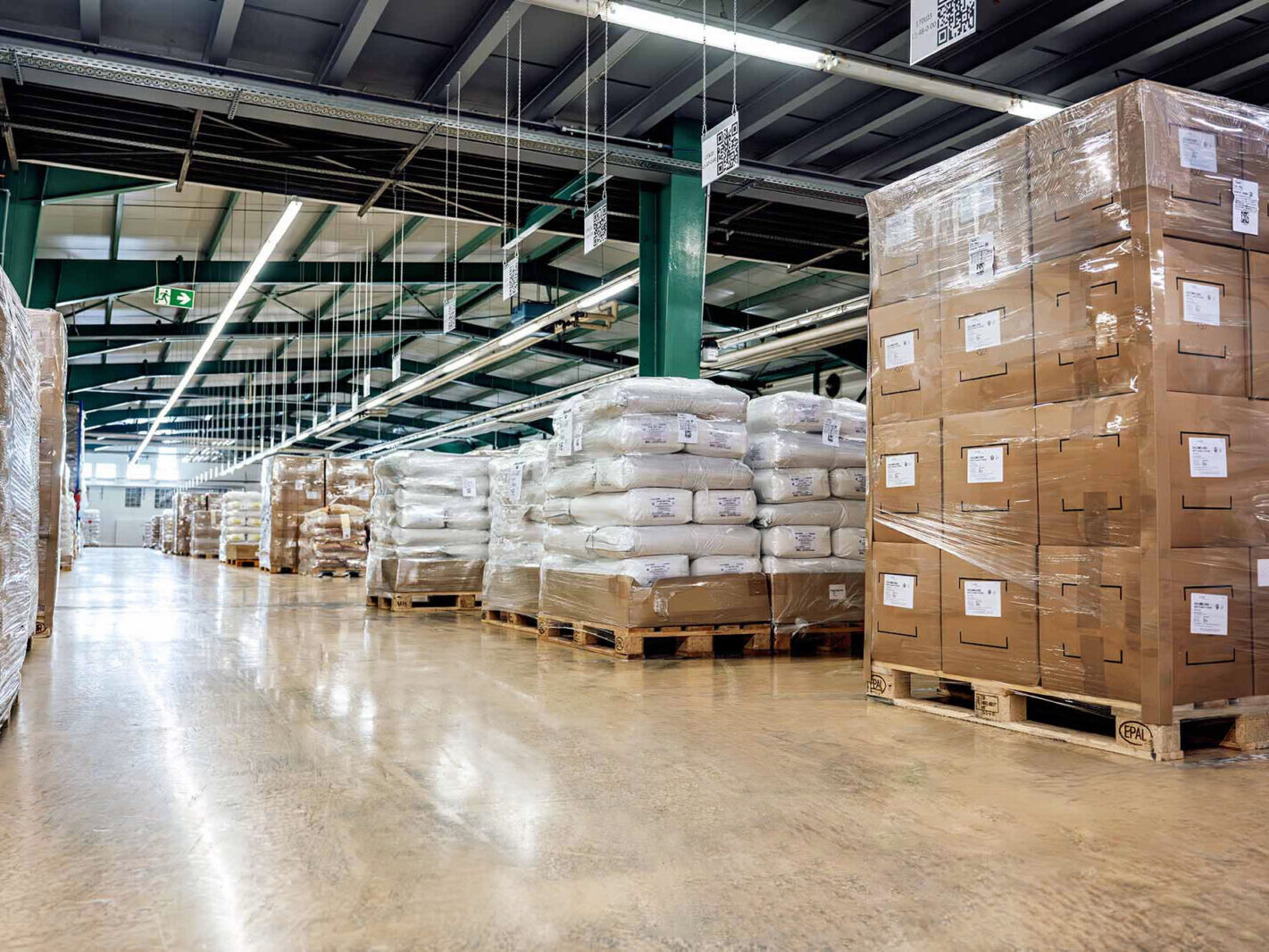 Warehouse aisle with palletized cargo and stacked boxes on forklifts racks in a logistics facility