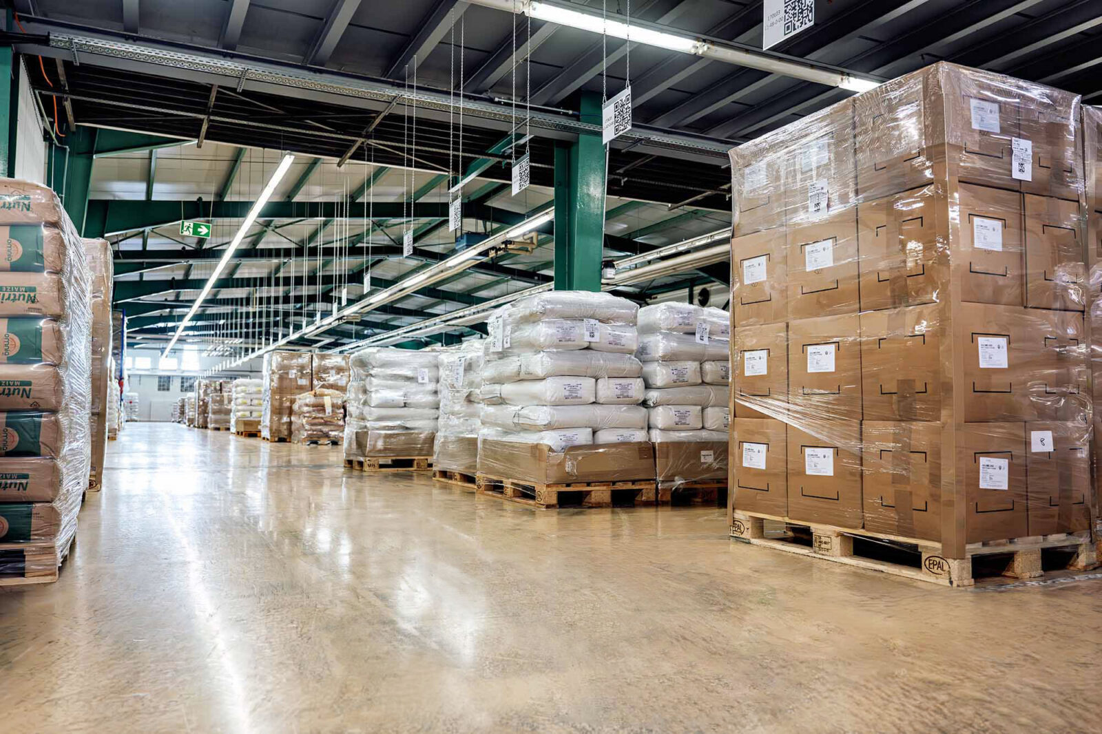 Warehouse aisle with palletized cargo and stacked boxes on forklifts racks in a logistics facility