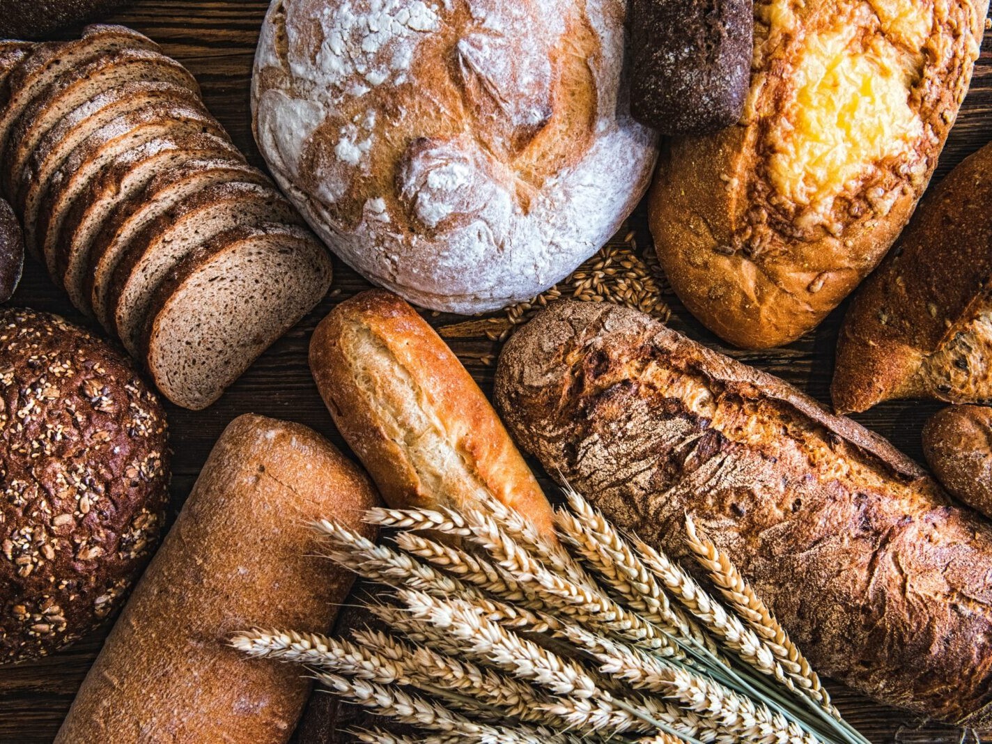 Rustic assortment of freshly baked artisan breads and rolls with whole wheat and rye grains on wooden table