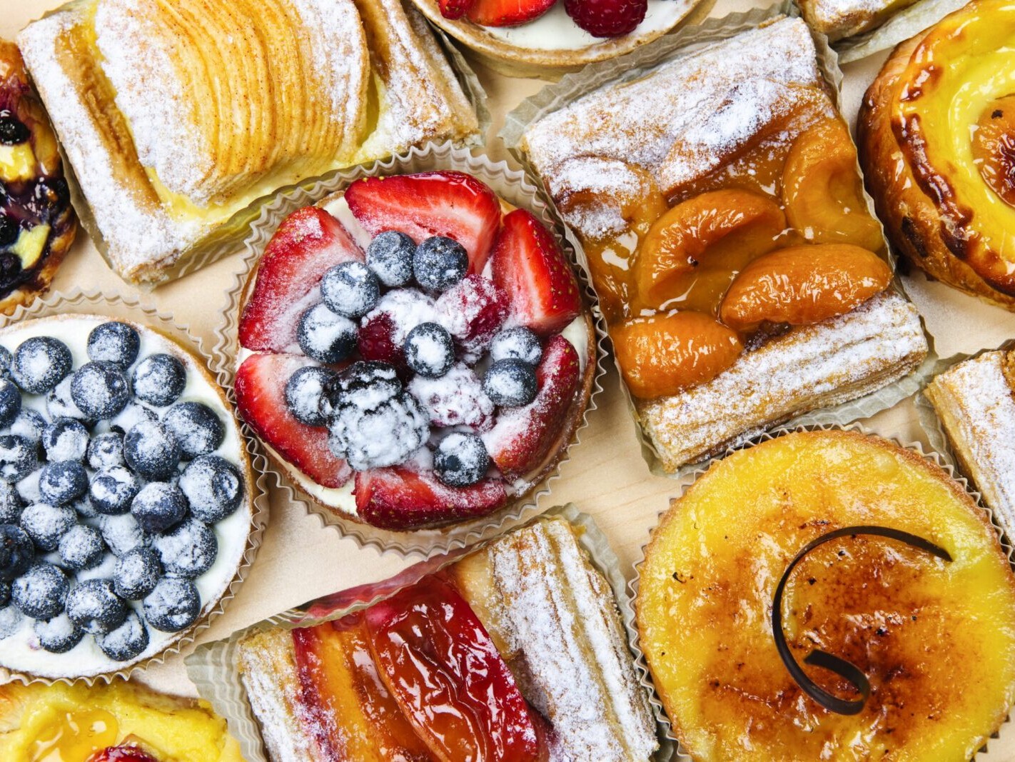 Assorted jam tarts, fruit pastries and powdered pies on parchment—strawberry, blueberry, apricot and lemon desserts