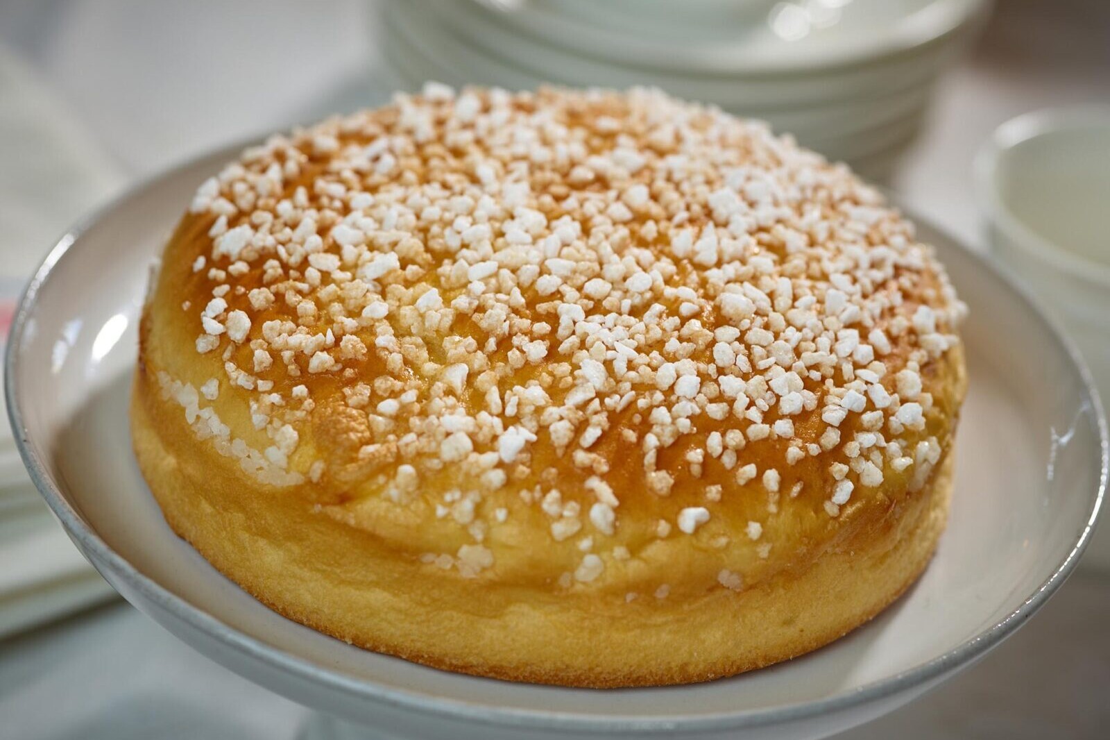 Salted caramel cake topped with crunchy sugar pearls on a white plate, close-up dessert photo