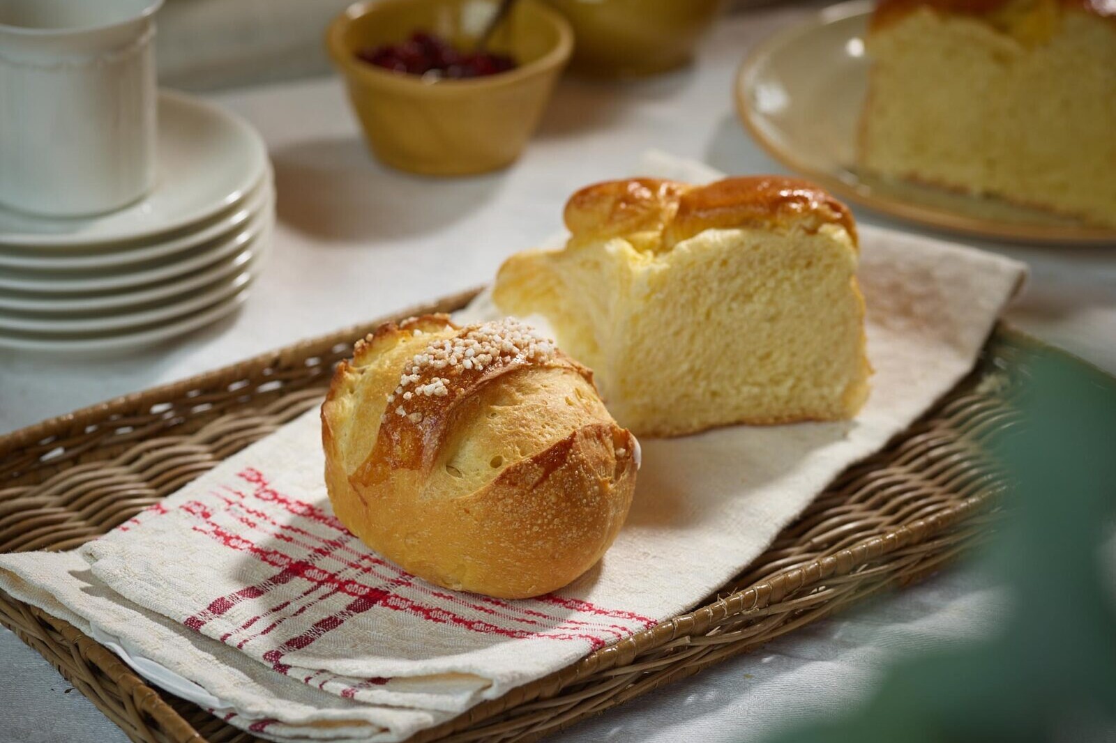 Warm baked bread rolls and golden butter loaf on a basket-lined tray for breakfast or snack