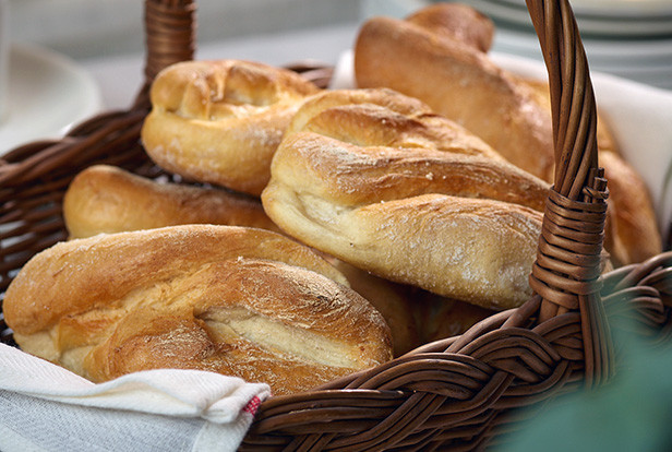 Freshly baked baguette rolls in a wicker basket with warm golden crust.