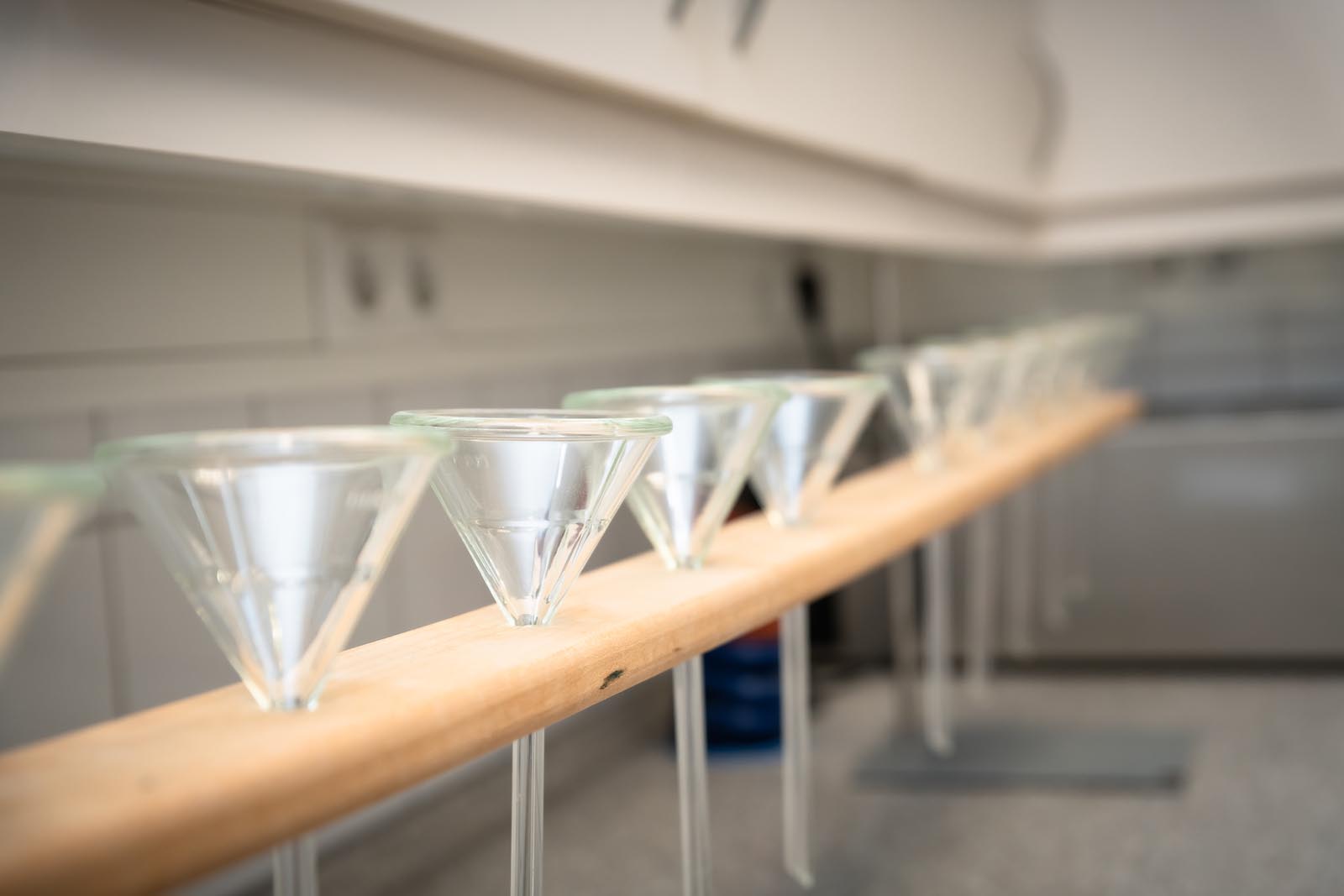 Martini glasses arranged on wooden railing in blurred bar interior, ready for drinks at a home party