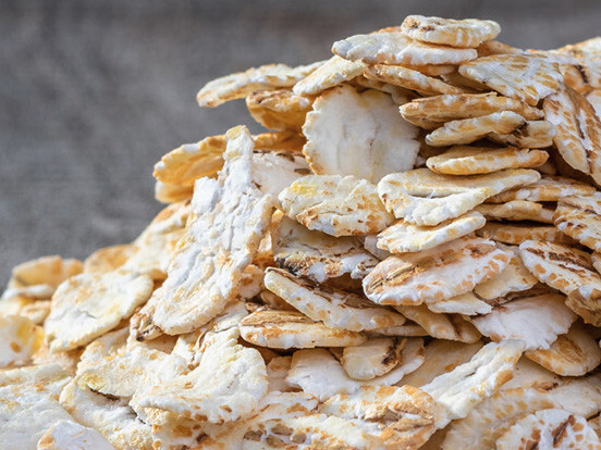 Stack of crunchy fried cassava chips with golden seasoning on a gray background, close-up food photo