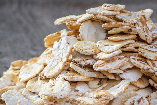 Stack of crunchy fried cassava chips with golden seasoning on a gray background, close-up food photo