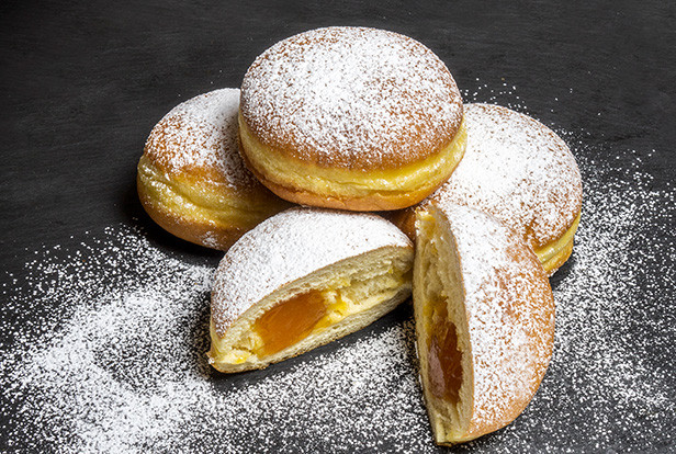 Powdered sugar filled pastries on slate, golden custard cream filling—close-up dessert photo